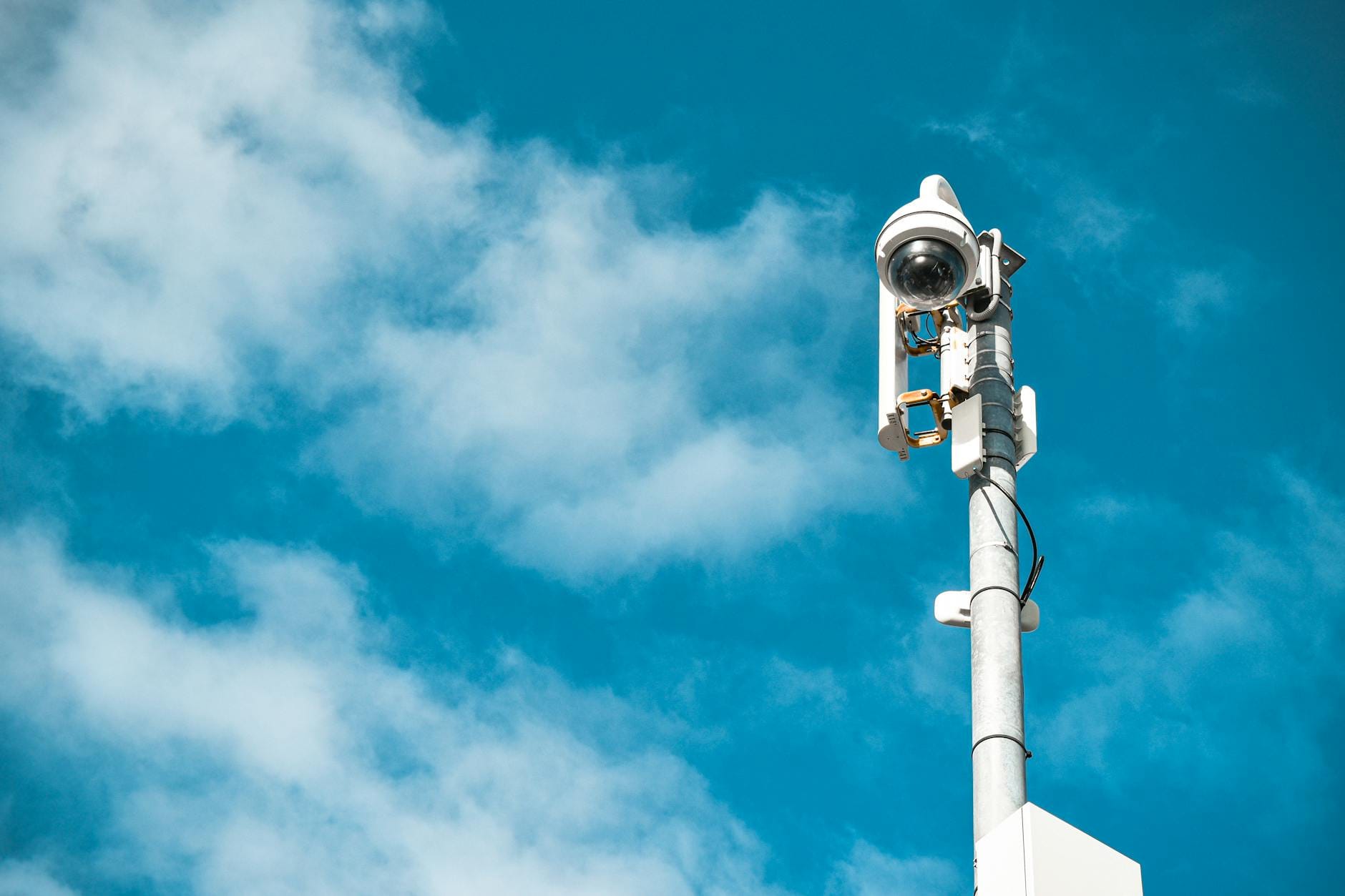 Kamera monitoringu na słupie na tle bezchmurnego, niebieskiego nieba