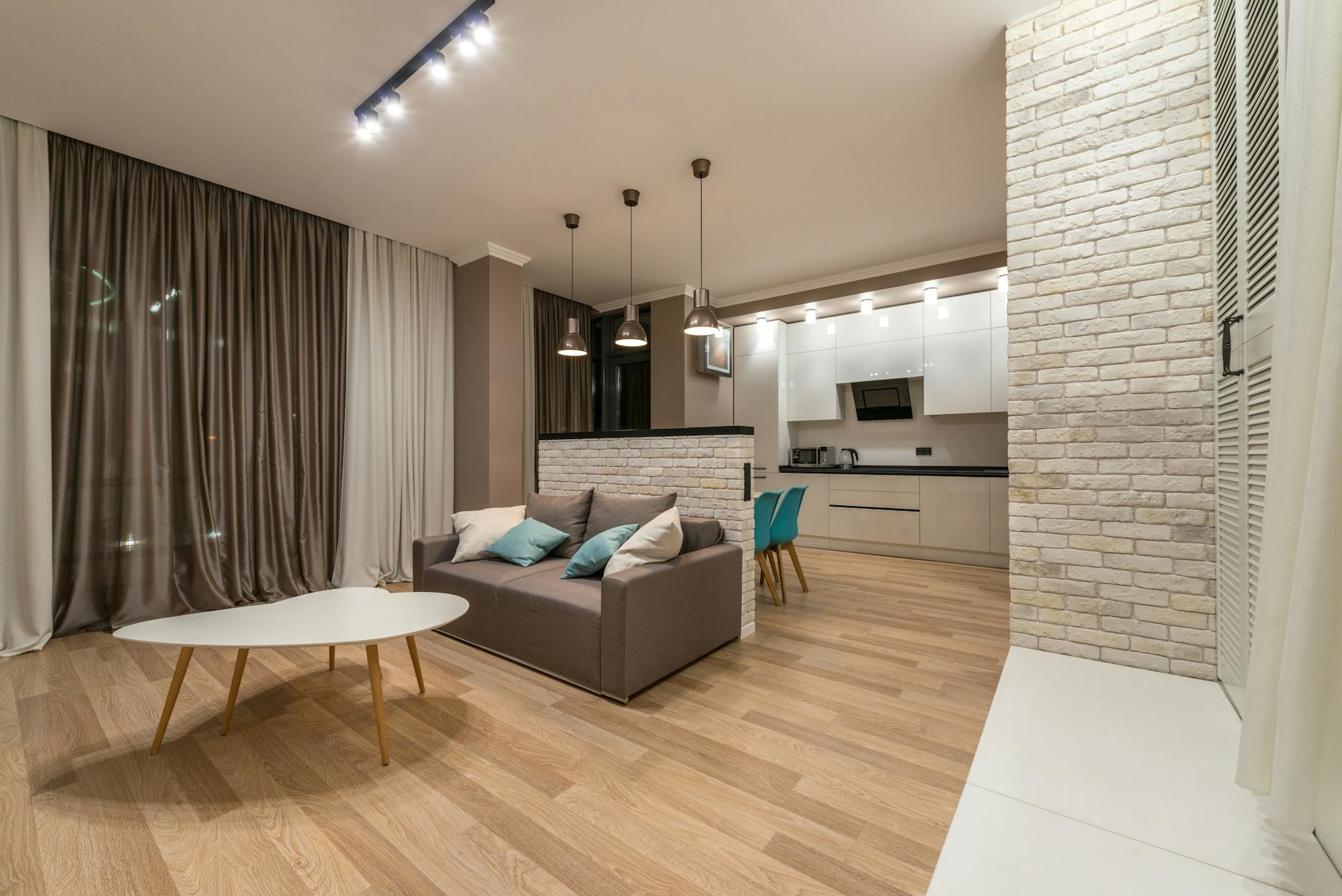 Nowoczesny salon z beżową sofą i stołem przy aneksie kuchennym