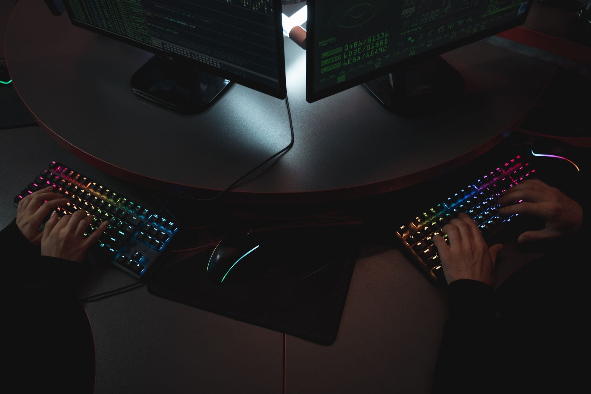 Specjaliści cybersecurity przy biurkach z kolorowymi klawiaturami RGB