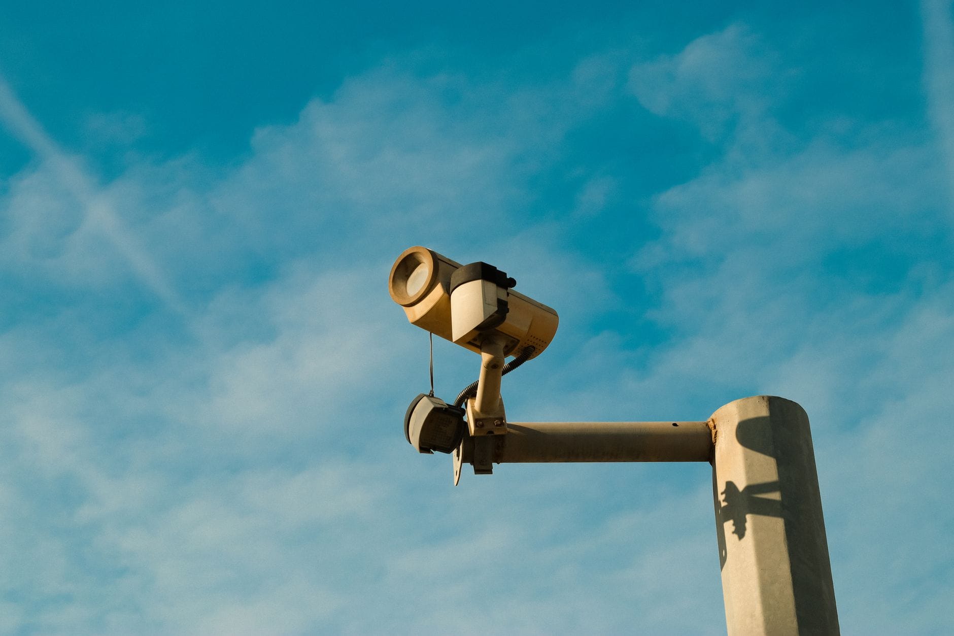 Zewnętrzna kamera monitoringu na tle jasnego, błękitnego nieba